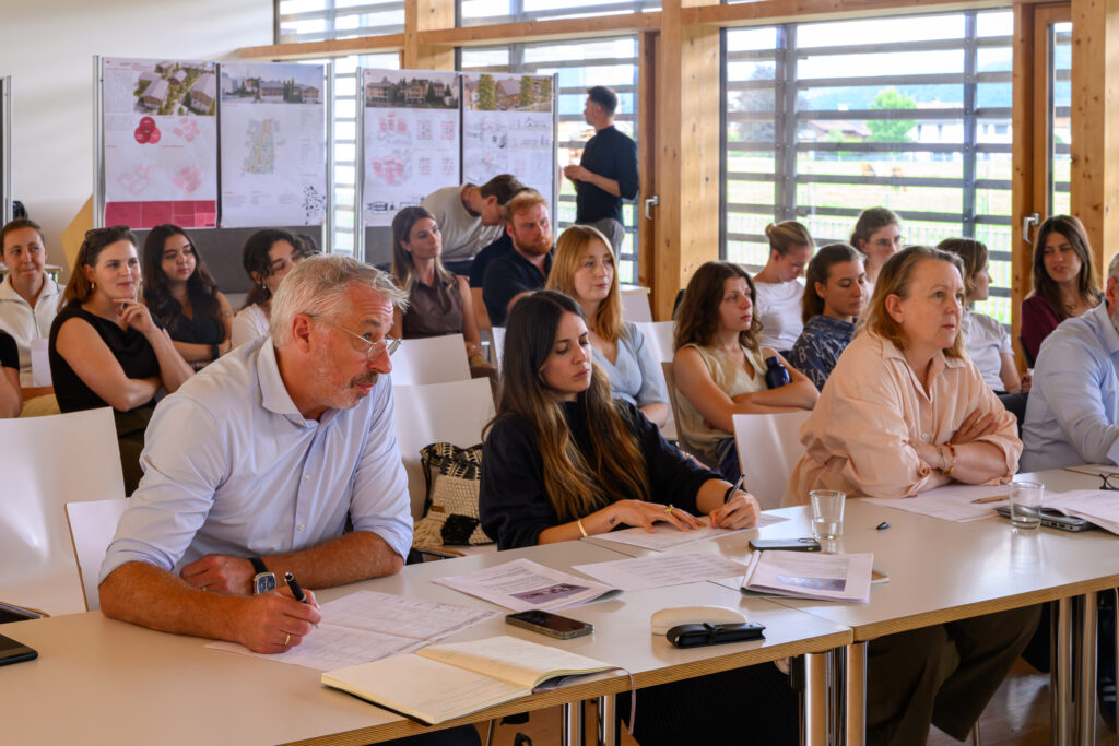 Studierende der Fachhochschule Salzburg sowie Vertreter der Fachjury folgen aufmerksam der Präsentation eines Bebauungskonzepts